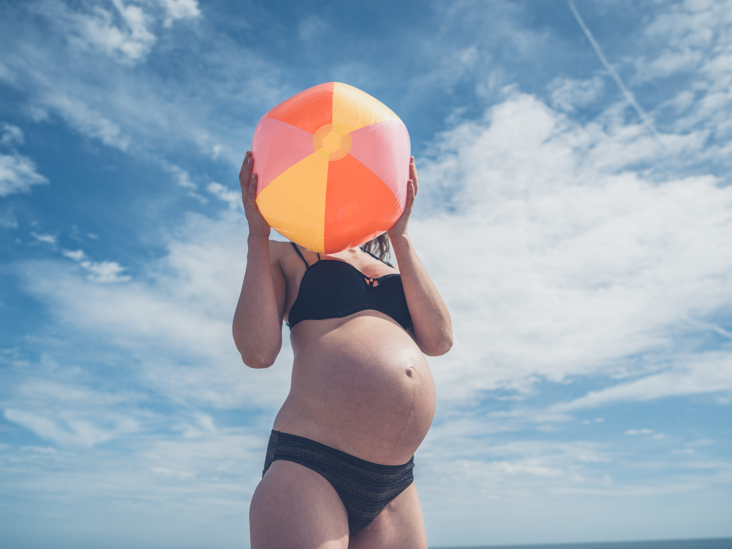 Pregnant woman staying cool at beach.