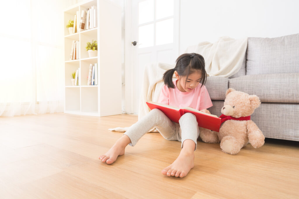 young girl reading to her teddy bear