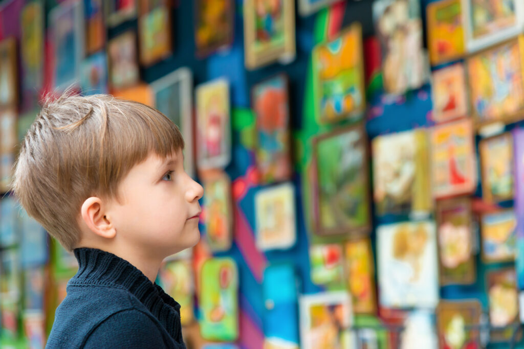 child looking at all his framed artwork