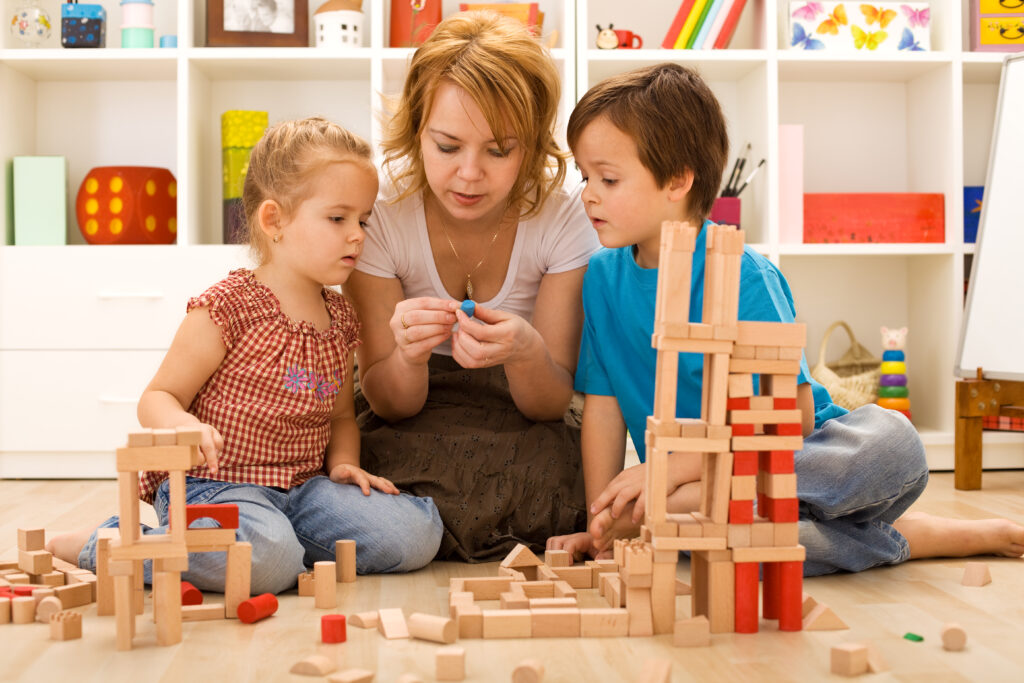 mom and kids sitting on floor building blocks