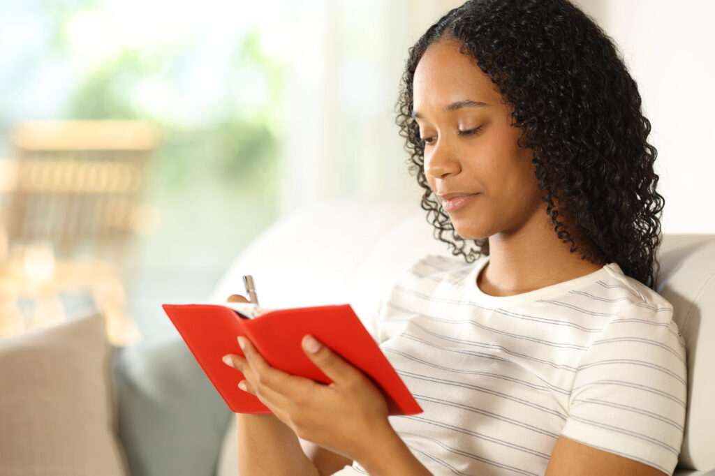 African American woman writing in journal.